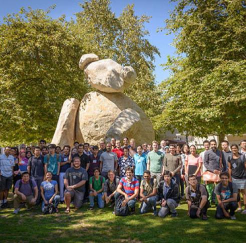 A large group of people posing in front of a sculpture